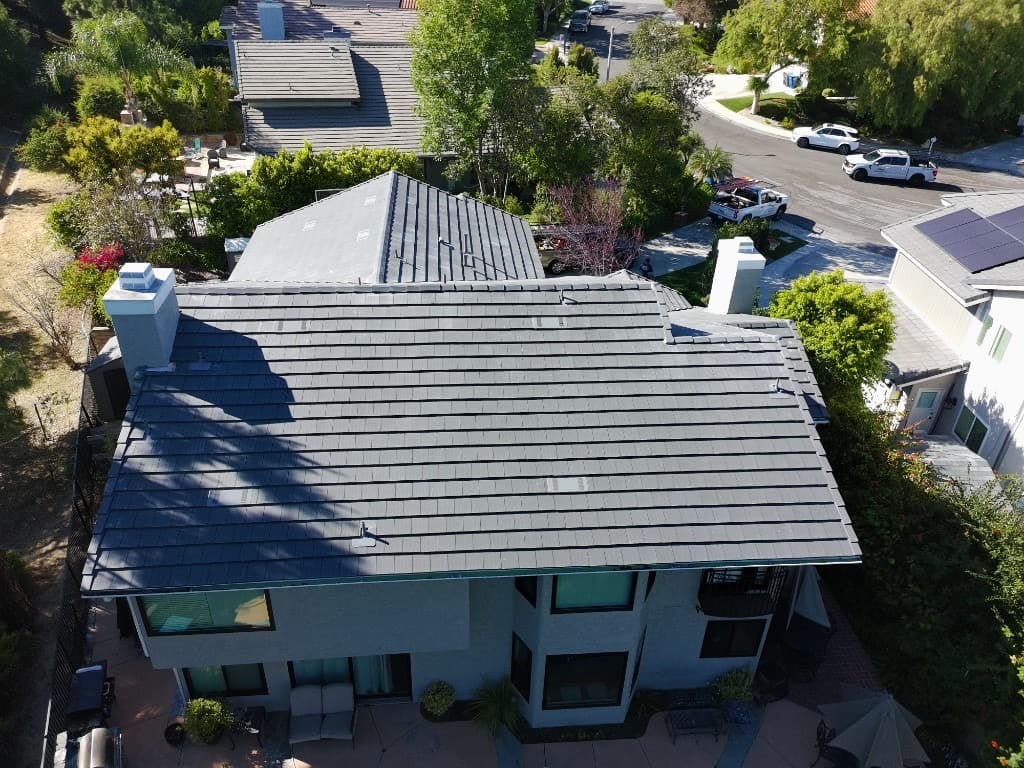 Aerial view of a white building with complex roofing near a residential street