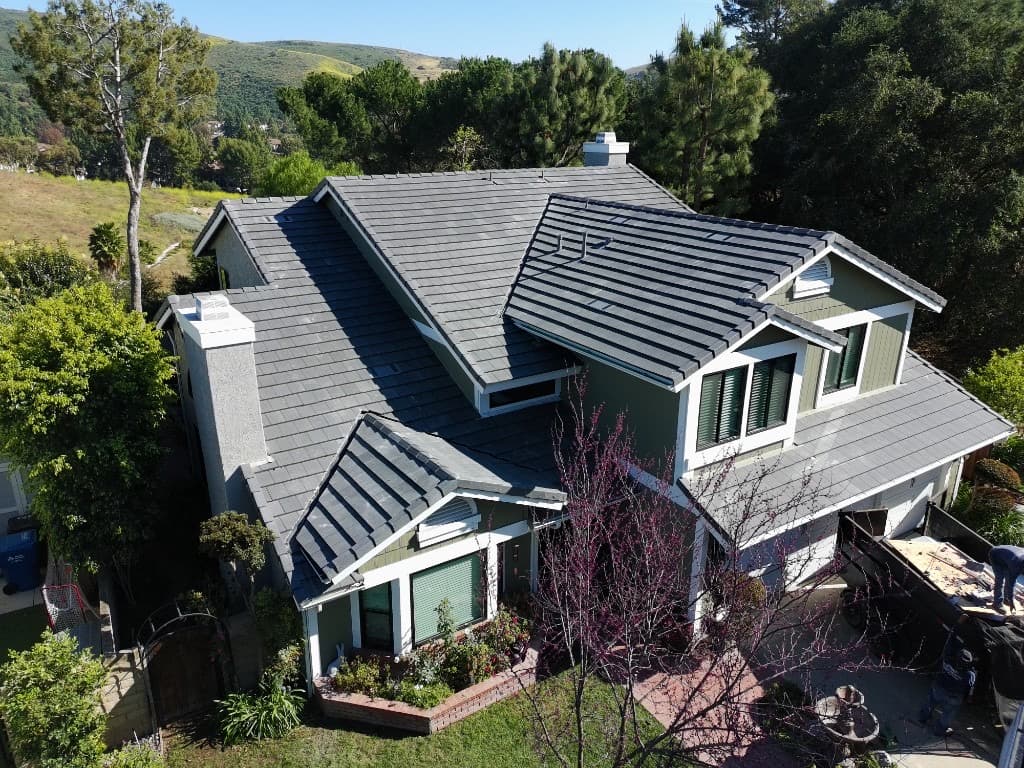 Large home with a modern dark grey shingle roof surrounded by trees