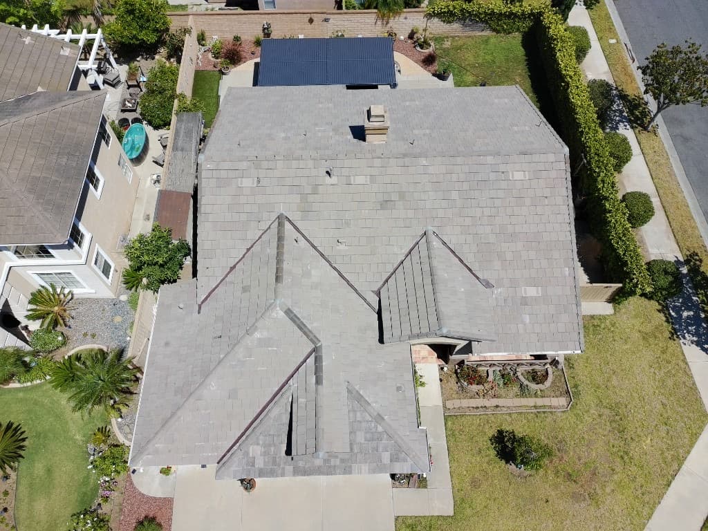 Aerial view of a home with dark grey shingle roofing and backyard