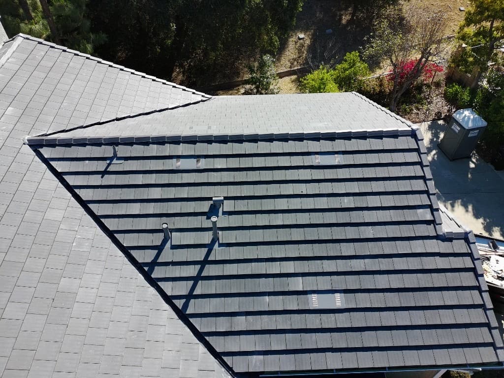 Top-down view of a suburban home with a grey tile roof and backyard pergola