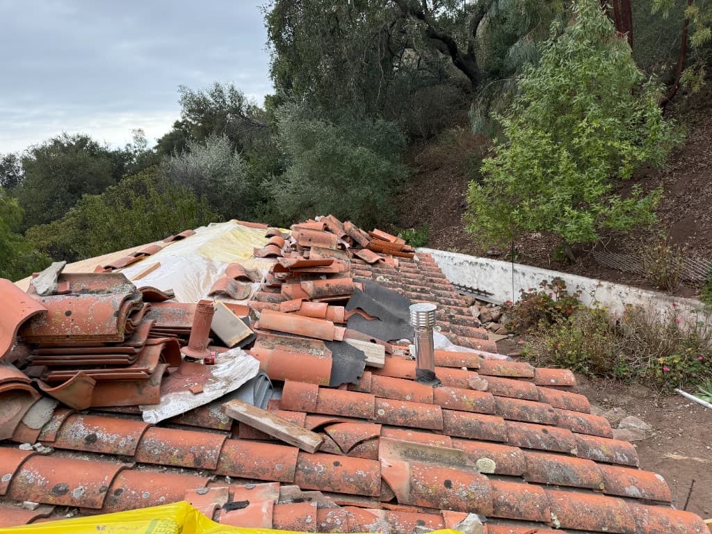 Terracotta tile roof during lift and reset, with tiles stacked before underlayment replacement