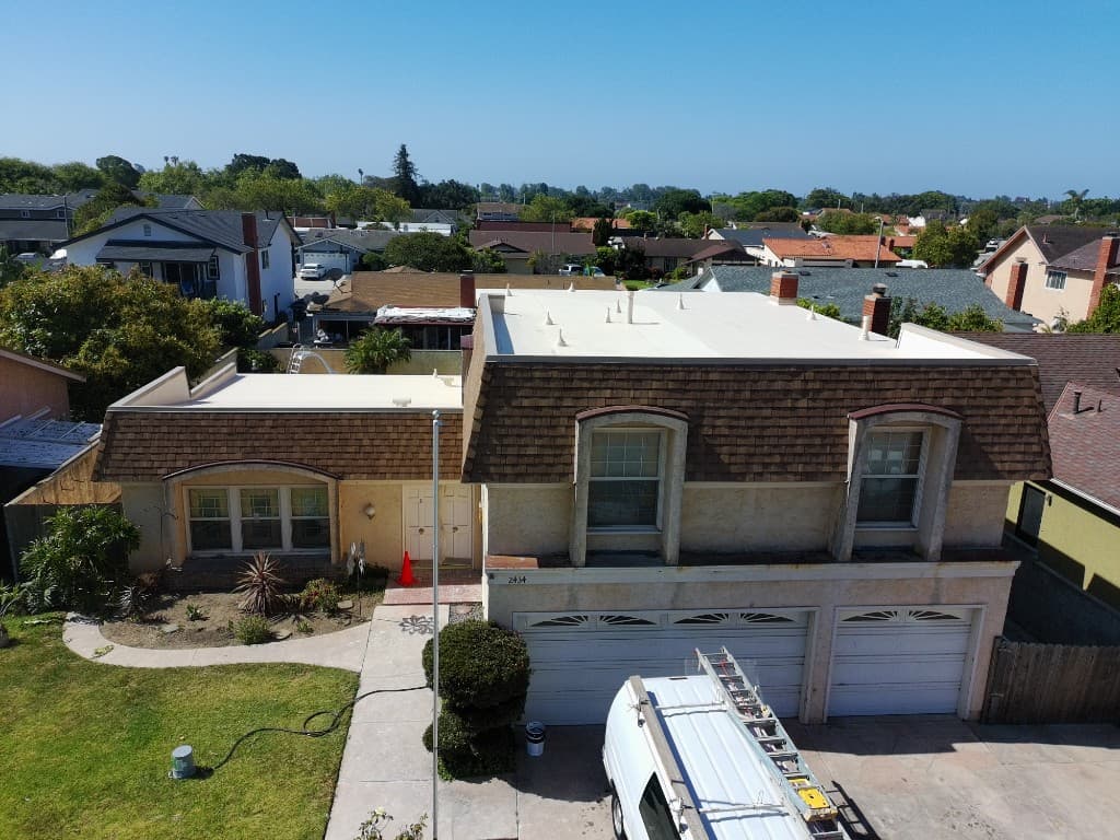Aerial view of the same home after roof replacement with new brown asphalt shingles and white flat roof sections